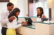 © Monkey Business - Couple Checking In At Hotel Reception Using Digital Tablet