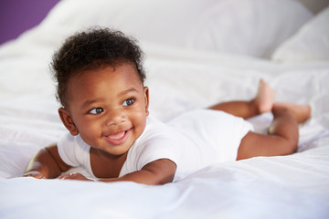 cute baby lying on tummy in parent's bed