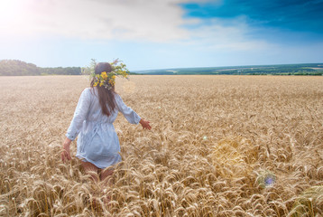 Beautiful girl in  wreath in the field of ripe wheat with lens f