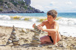 sunburnt boy plays with pebbles on the beach