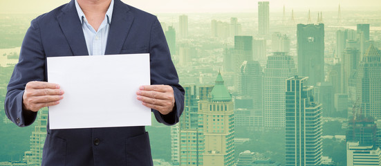 Business man hands holding blank paper with cityscape background