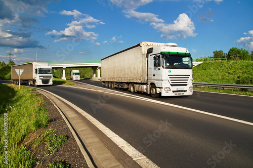 Naklejka samoprzylepna Białe ciężarówki jeżdżące autostradą po okolicy