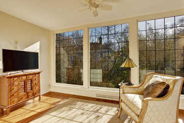 Bright sunroom with antique chair and tv