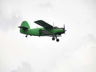 Wall Mural - small green airplane flying in overcast sky