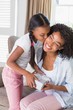 © WavebreakMediaMicro - Pretty mother sitting on couch offering daughter a gift