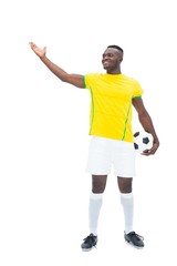 Football player in yellow standing with the ball