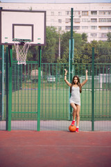 Poster - Beautiful young woman playing basketball outdoors