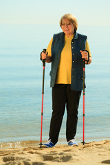 active woman senior nordic walking on a beach