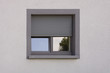 canvas print picture - Dunkles Kunststofffenster mit Rollladen in grauer Fassade