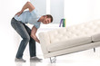 © BlueSkyImages - Handsome man lifting sofa and feeling pain.