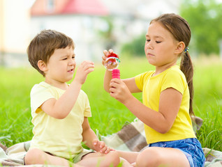 Little girl and boy are blowing soap bubbles