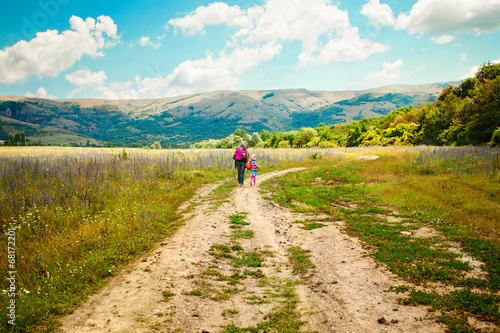 Fotografia, Obraz Mother and daughter walk on road through field