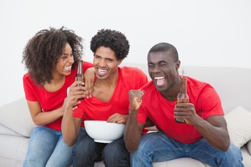 Wall Mural - Football fans sitting on couch cheering together