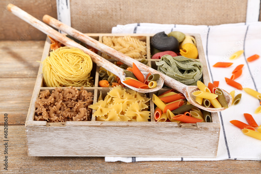 Colorful pasta in wooden box on wooden table background