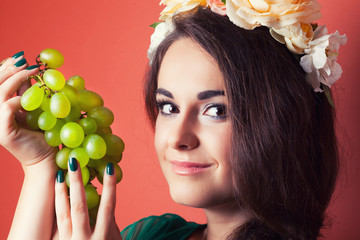 beautiful young woman wearing wreath and holding green grapes ag