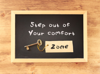 Wall Mural - the phrase step out of your comfort zone written on blackboard