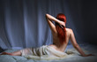 Back view of a naked redhead woman sitting in bed