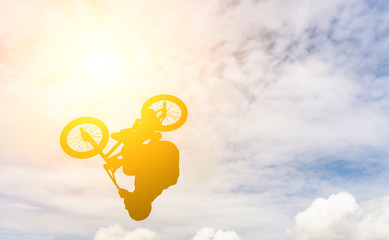 Man doing an jump with a bmx bike against sunshine sky.