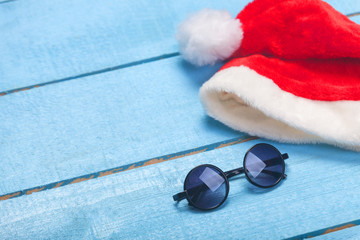 Sunglasses and christmas hat on blue wood