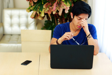 Sticker - Young tired man sitting at the table with laptop at home