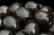 Stoned black olives on black background.