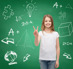 Wall Mural - smiling little girl in white showing victory sign