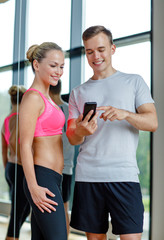 Canvas Print - smiling young woman with personal trainer in gym