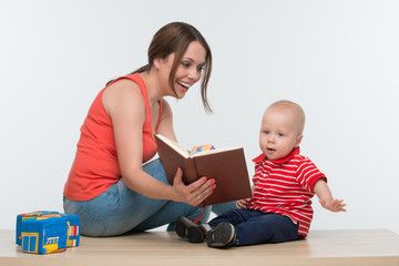 Portrait of young attractive mother and her cute toddler reading