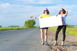 © adam121 - Two young women stand with a blank banner