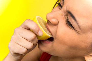 Cute girl eating fresh lemon.