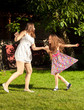 brunette woman an young girl holding ands and dancing at yard