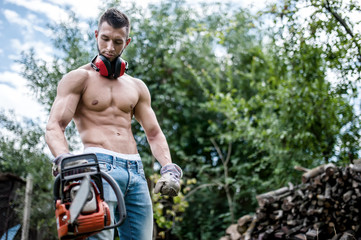 Wall Mural - portrait of sexy man with chainsaw and protective gear ready