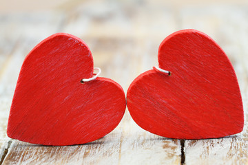 Two red wooden hearts on wooden surface