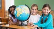 © WavebreakmediaMicro - Cute pupils sitting in classroom with globe