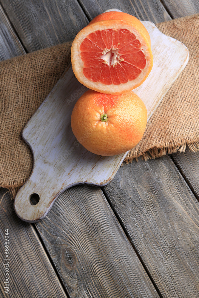 Ripe grapefruits on cutting board, on wooden background