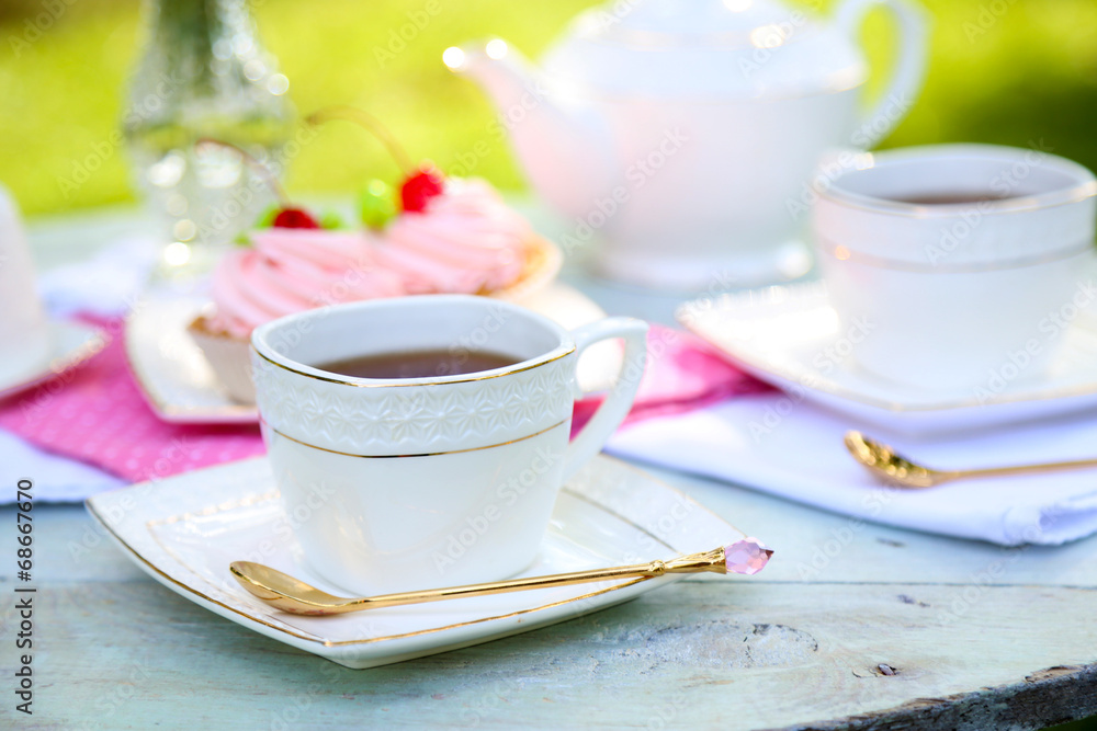Coffee table with teacups and tasty cakes in garden