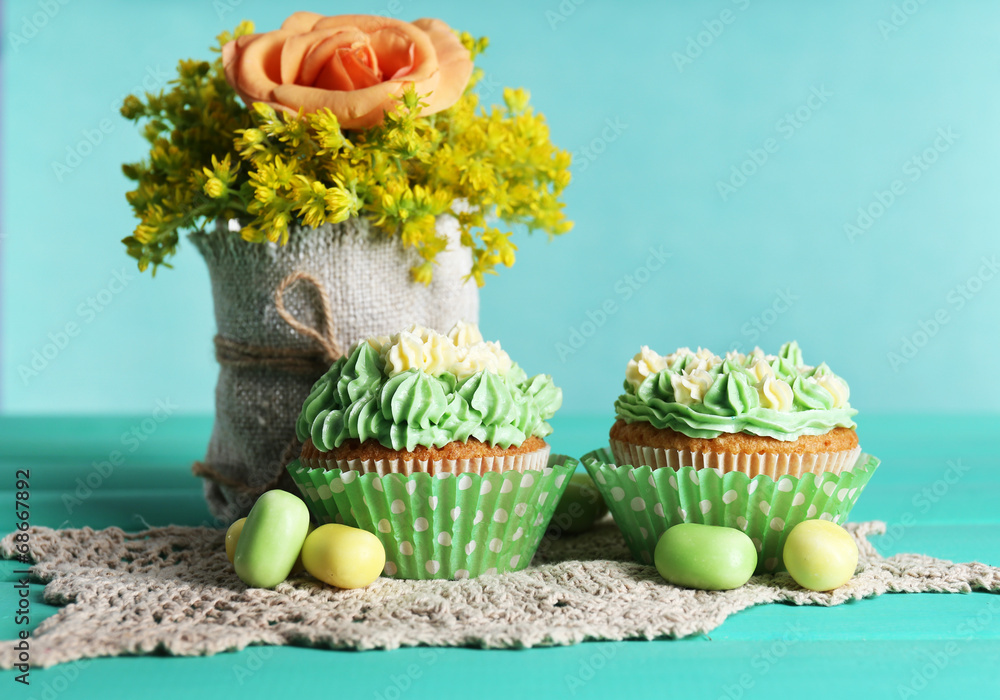 Tasty cupcakes on table, on turquoise background