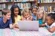© WavebreakmediaMicro - Cute pupils looking at laptop in library