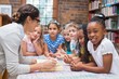 © WavebreakmediaMicro - Cute pupils and teacher reading in library