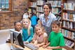 © WavebreakmediaMicro - Cute pupils and teacher looking at computer in library