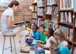 © WavebreakmediaMicro - Cute pupils sitting on floor in library