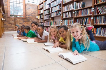 Wall Mural - Cute pupils and teacher lying on floor in library