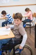 © WavebreakmediaMicro - Disabled pupil writing at desk in classroom