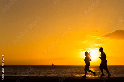 Naklejka samoprzylepna Sylwetka ludzi jogging na plaży z zachód deseń
