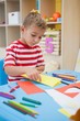 © WavebreakMediaMicro - Cute little boy folding paper shapes in classroom