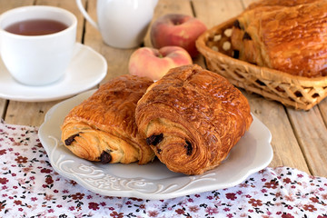 Wall Mural - Chocolate croissants on a plate with tea for breakfast