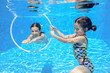 © Iuliia Sokolovska - Happy active kids swim in pool and play underwater