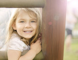 Fototapeta Tęcza - uśmiechnieta dziewczynka na tle drewnianego ogrodzenia