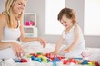 © WavebreakmediaMicro - Mother and daughter playing with building blocks on bed