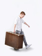 Young boy carrying big brown suitcase, walking